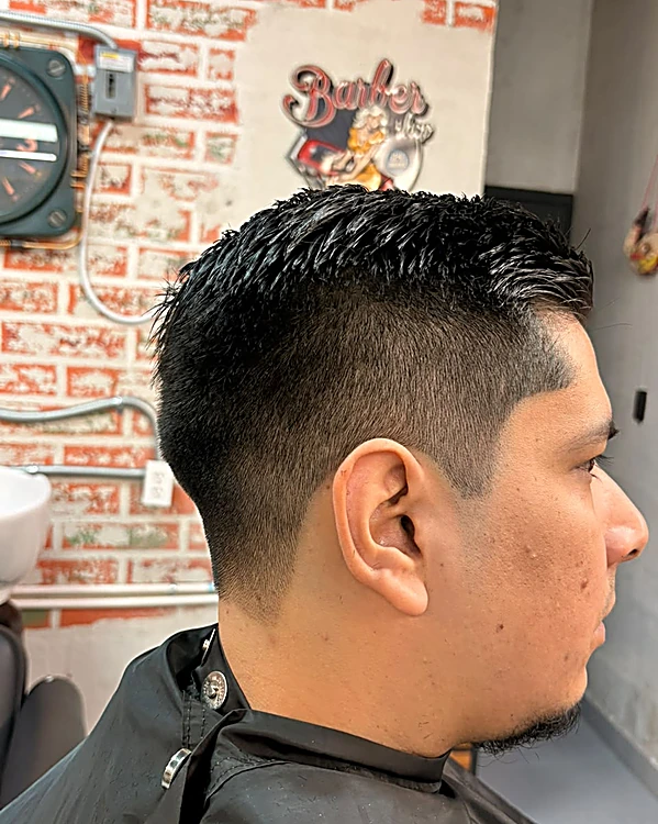 Fade a los lados con textura en puntas arriba, de perfil, frente al muro con la ilustración Barber
